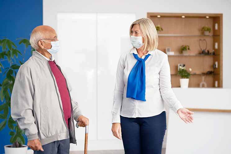 Audiologist greeting an older customer in a modern hearing care clinic.