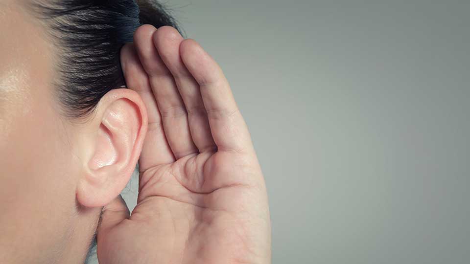 Hand cupped behind ear, symbolizing listening or hearing attentively.