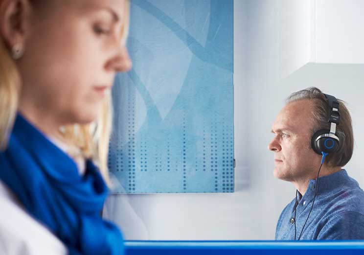 Man wearing headphones during a hearing test in a soundproof booth.