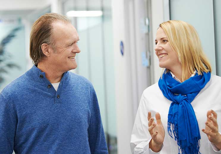 Man speaking with an audiologist in a HearingLife Centre hallway.