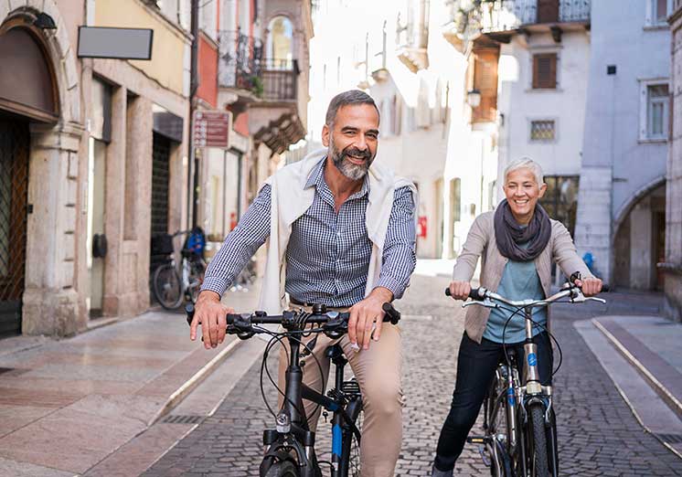 Couple riding bicycles on a cobblestone street in a picturesque urban setting