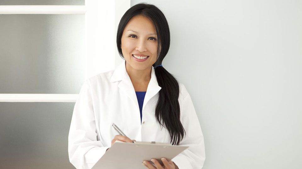 HearingLife audiologist holding a clipboard in a white lab coat.