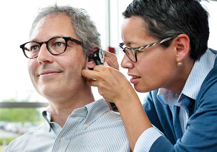 Man receiving an ear examination from a hearing care professional.