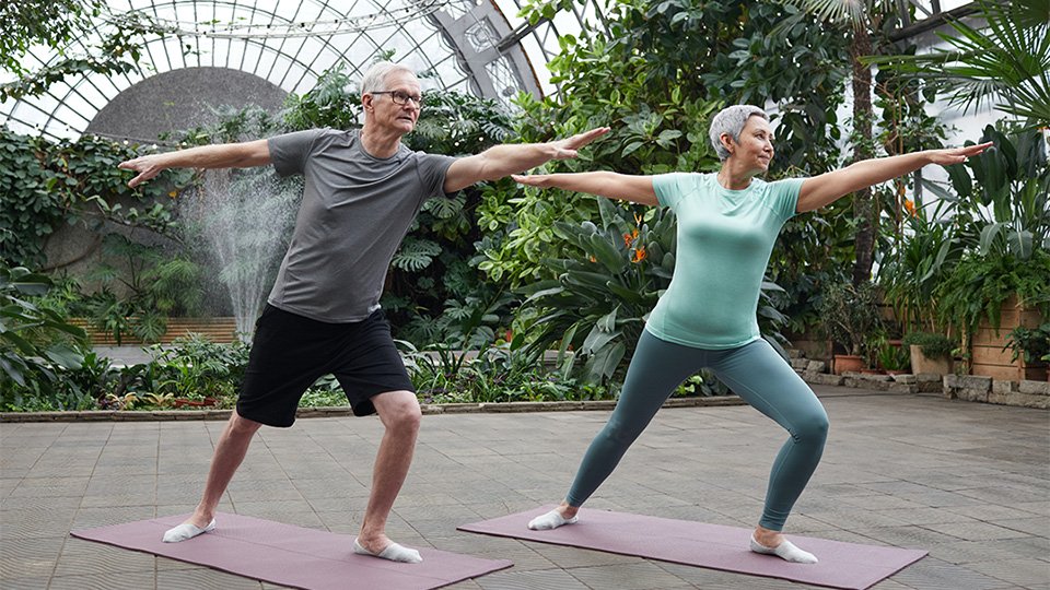 Man and woman doing yoga in greenhouse
