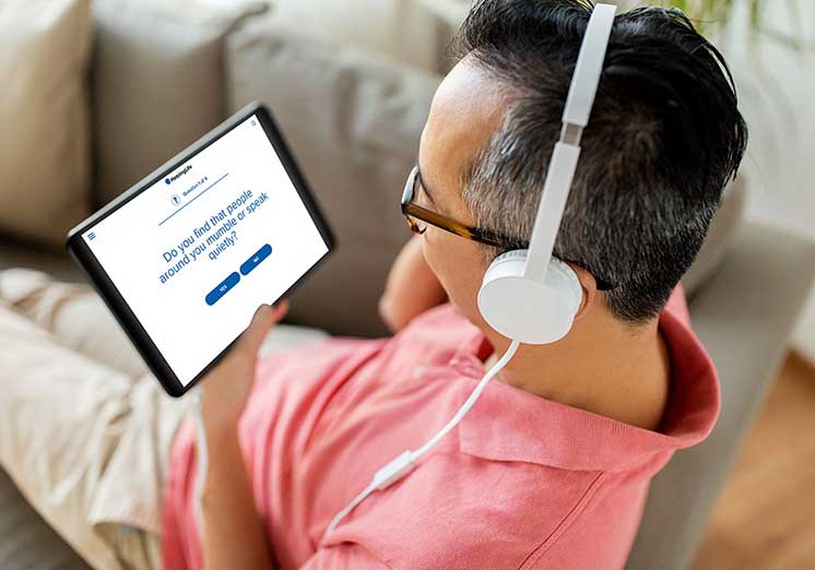 Man wearing headphones while completing an online hearing test on a tablet.