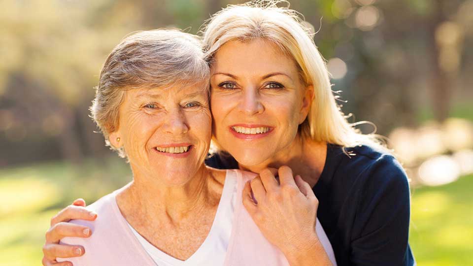 Caring moment between two women outdoors, highlighting empathy and connection in hearing care.