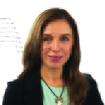 A professional woman with shoulder-length brown hair wears a black blazer, a mint-green top, and a circular pendant necklace, posing against a plain white background in a polished setting. No text visible.