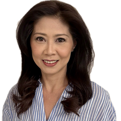 A woman with dark, shoulder-length wavy hair is dressed in a blue and white striped shirt. Her face is intentionally blurred, focusing on the upper body and hairstyle in a neutral, undefined environment. No text or visible hearing aids are present.