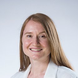 Anna Jewulski, hearing care specialist with long blonde hair, wearing a white professional coat.