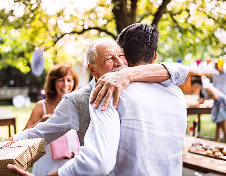 Image show grand dad give his son a hugh at a birthday