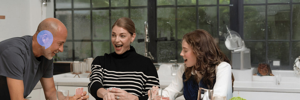 Man wearing Oticon Zeal hearing aids and playing card game with family