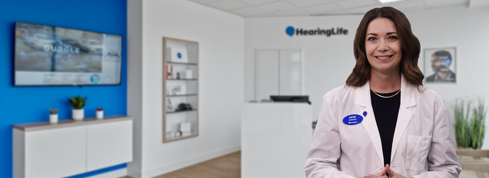 Katie Koebel, Audiologist and Senior Manager at HearingLife, wearing a white coat in a modern hearing care clinic.