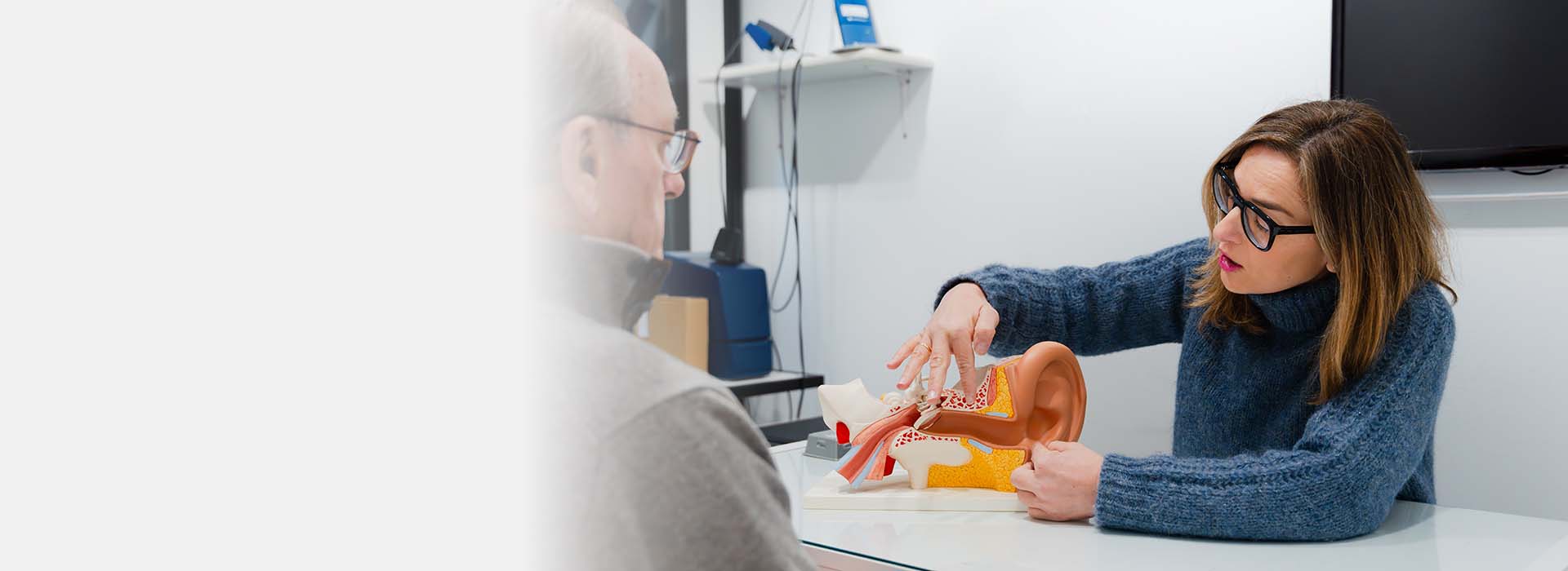 Audiologist showing ear model to client