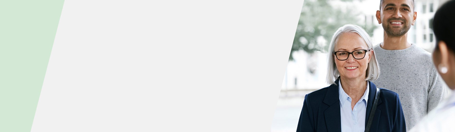 A senior woman wearing a blue jacket and collared shirt engages in conversation; background shows soft-focus outdoor elements, and partial views of two others are visible. No clear branding or text present.