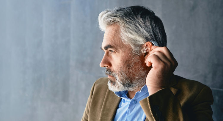man adjusting hearing aid