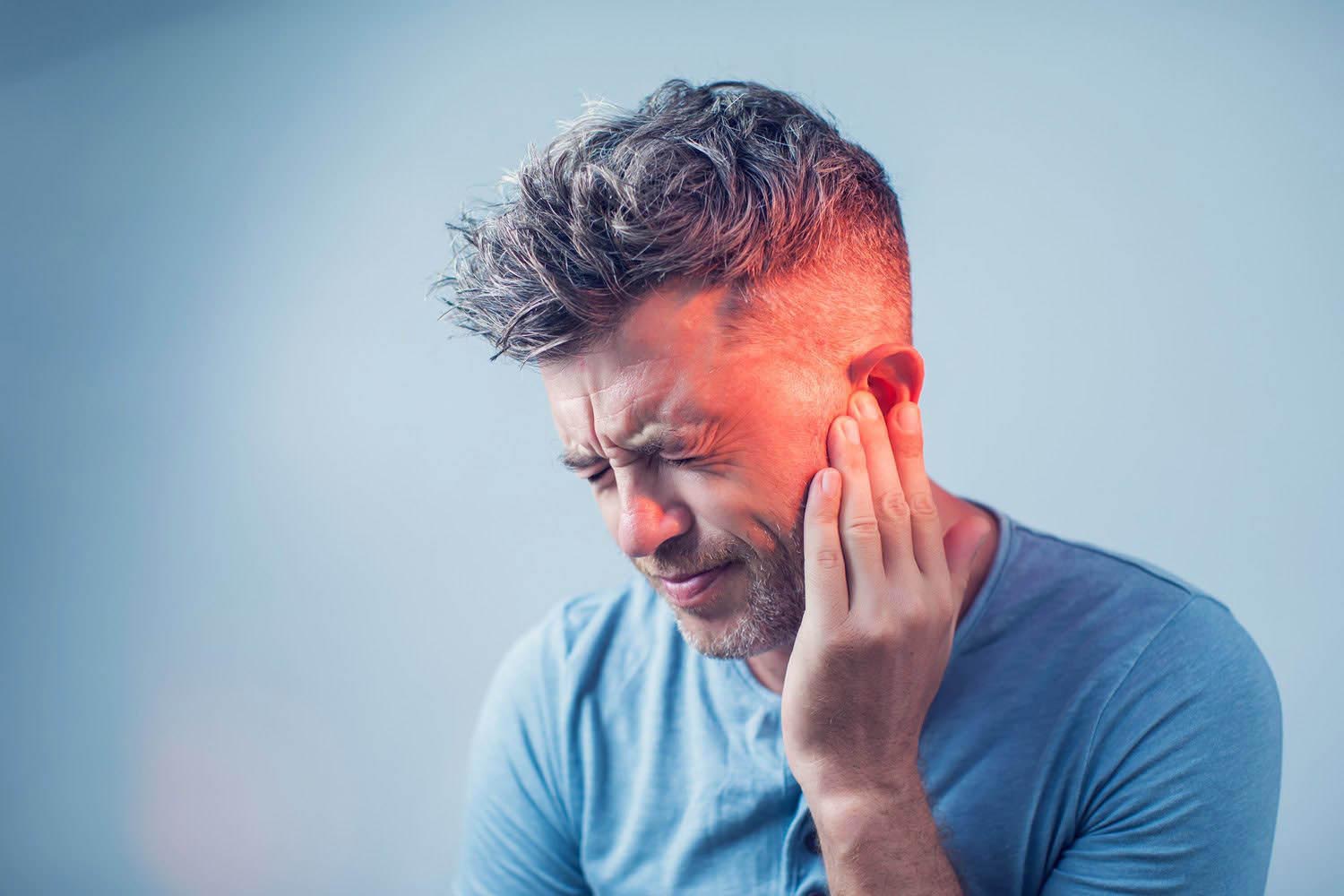 male having ear pain touching his painful head isolated on gray background