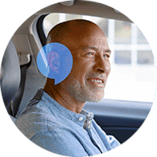 Man sitting in car with Oticon Zeal hearing aid in his ear. There is a blue HearingLife speech bubble overlay on his ear