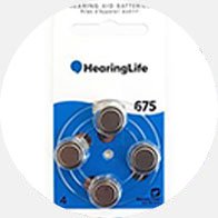 A HearingLife-branded pack of four button-style hearing aid batteries (size 675) is arranged in a circular holder against a blue background. The top label reads: ’Hearing Aid Batteries, Zinc Air - Mercury Free.’