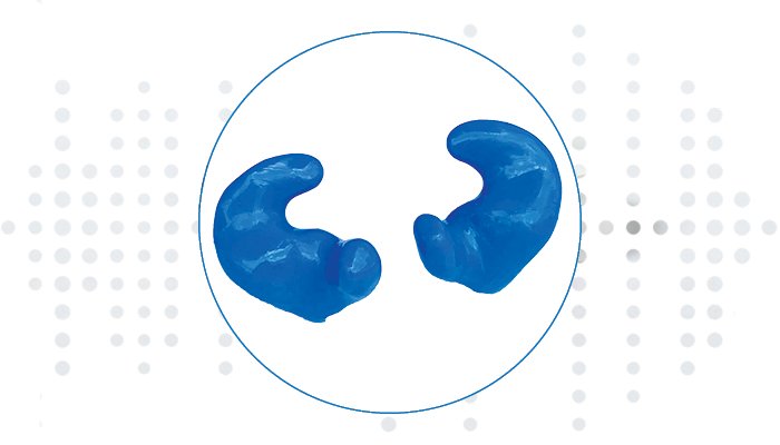 Custom blue earplugs sit within a circular frame, designed for noise reduction or hearing protection, showcased against a dotted white background resembling sound waves or audiology testing visuals. No text present.