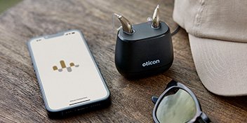 hearing aids in charger and smart phone with hearing aid app open