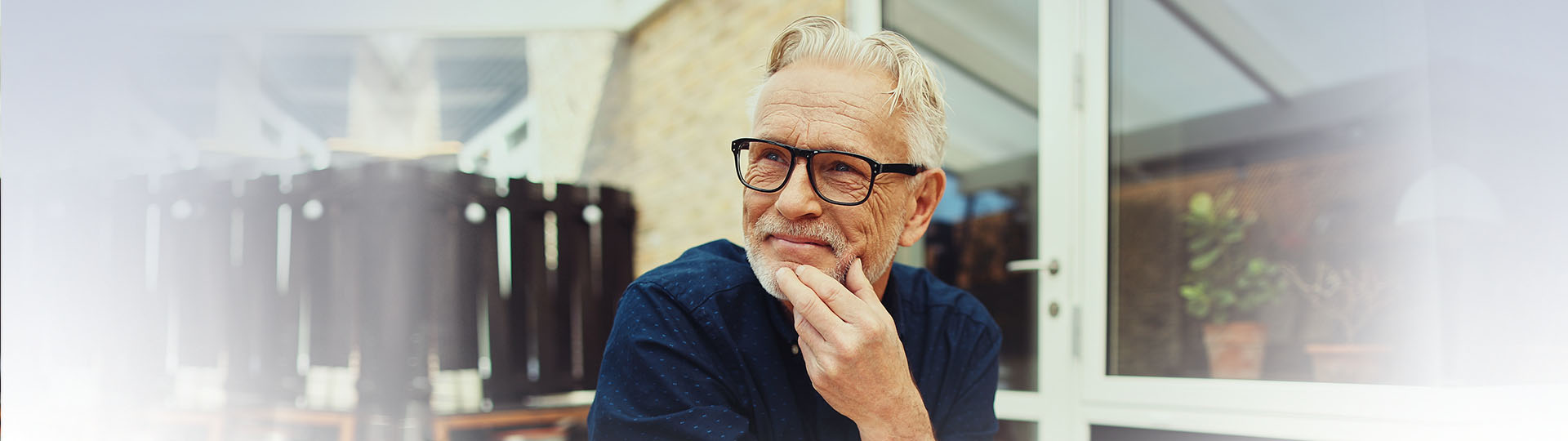 Senior man reflecting on hearing loss while sitting outdoors