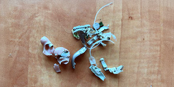 Broken hearing aid components scattered on a wooden surface