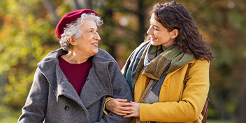 Two women enjoying a walk outdoors, sharing smiles and companionship.