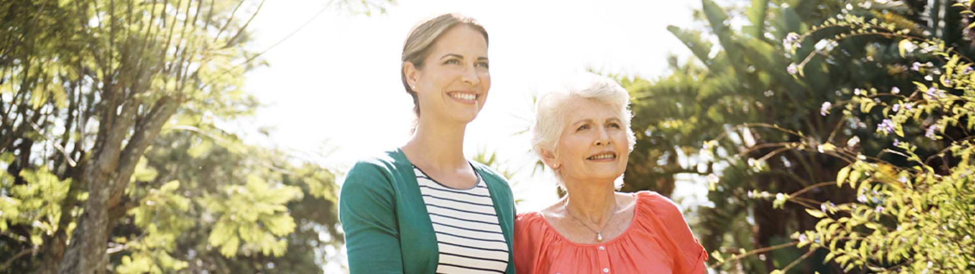 Caregiver supporting senior woman outdoors.