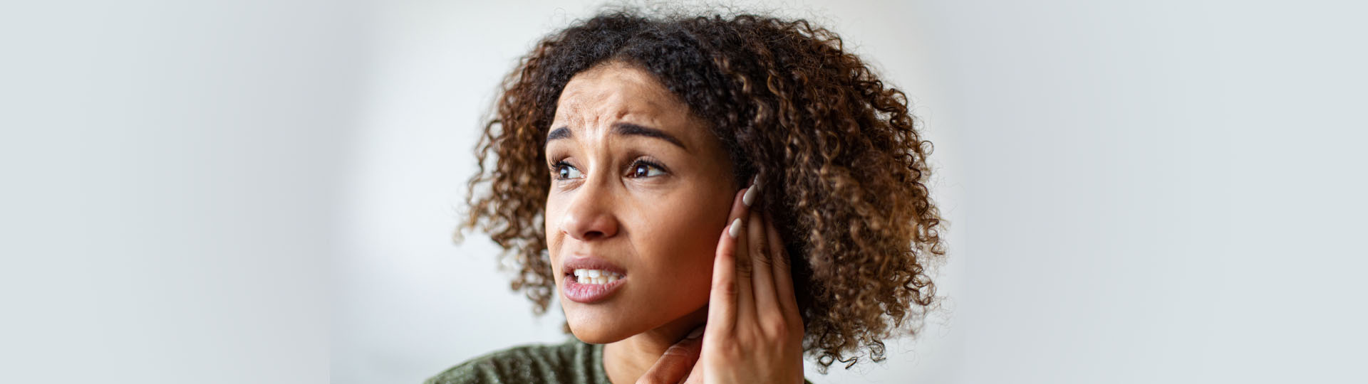 Woman holding her ear and expressing discomfort.