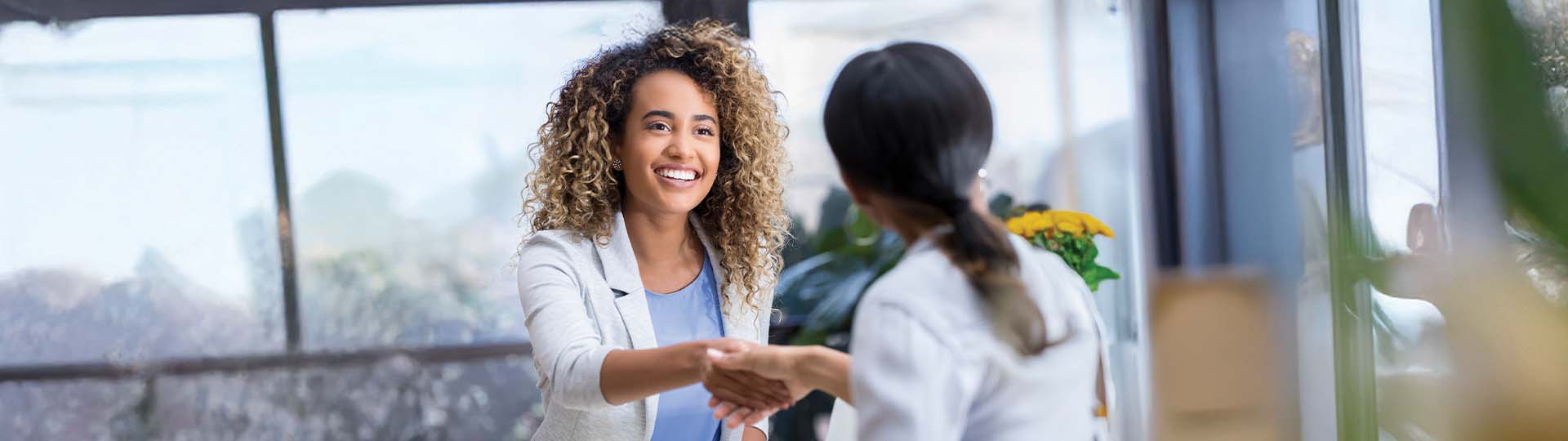 person shaking hands with a hearing care professional in a bright office setting
