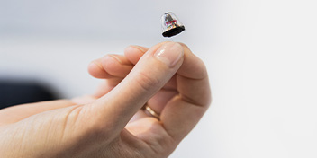 Hand holding a small hearing aid