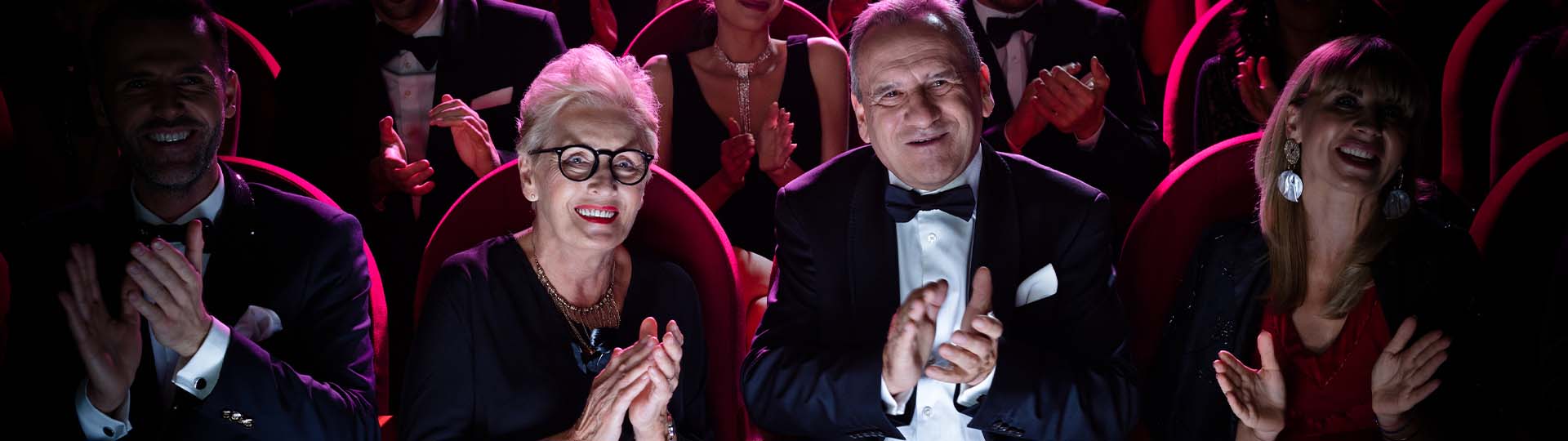 Couple enjoying a live performance and clapping in a theatre setting