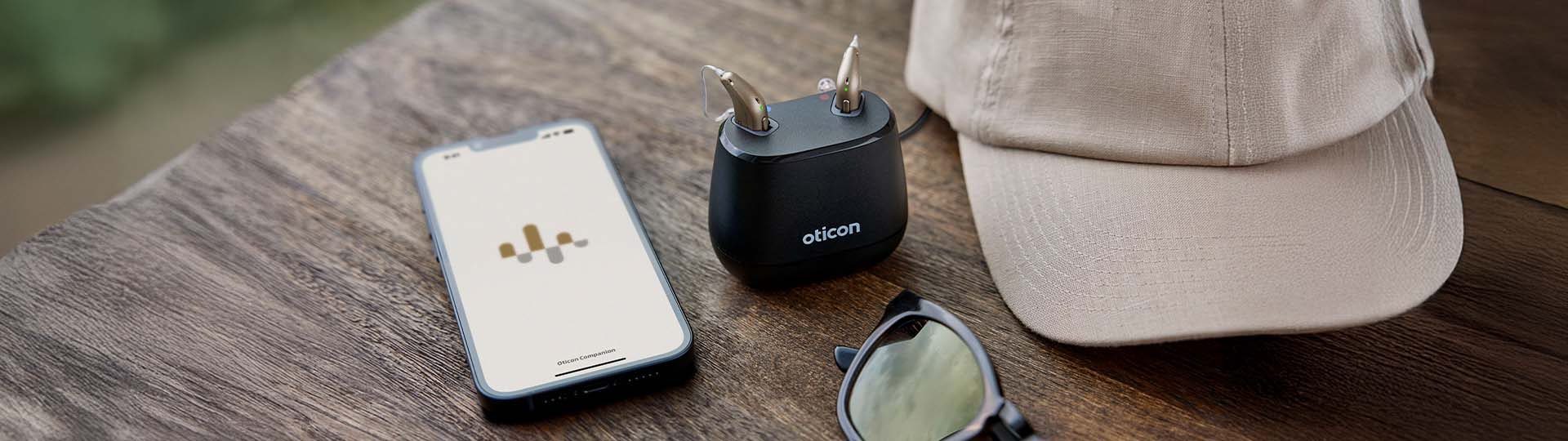 hearing aids in charger beside smartphone displaying hearing aid app