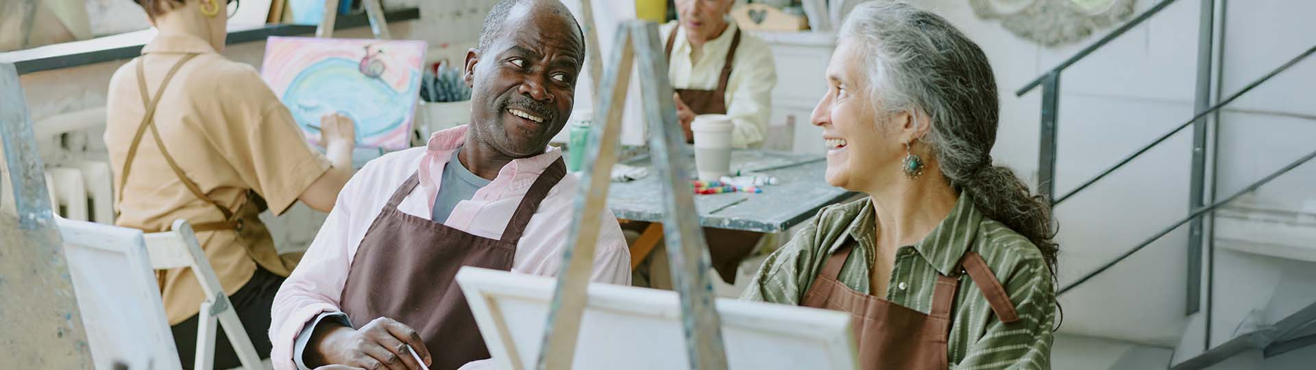 man and woman smiling at each other while participating in an art class