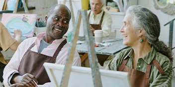 man and woman in an art class smiling at each other