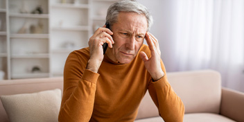 Man experiencing tinnitus discomfort while touching his ear.