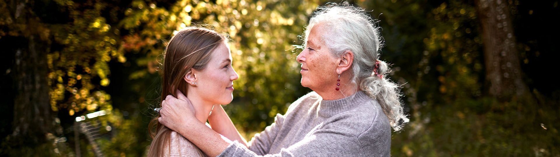 Grandmother embracing granddaughter in a sunny, outdoor setting