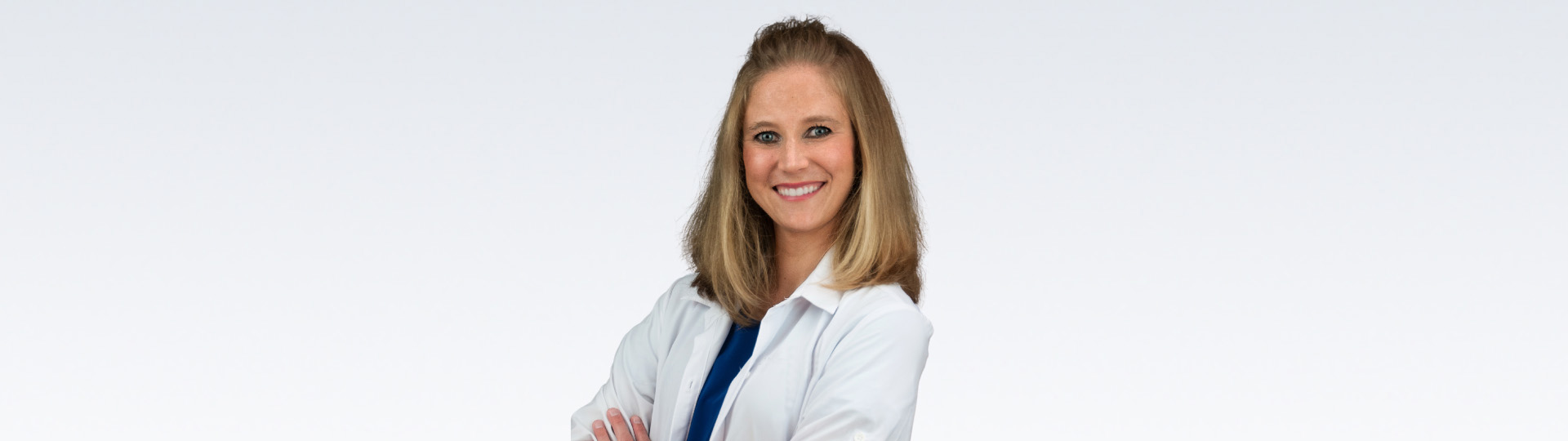 audiologist with crossed arms wearing a white coat