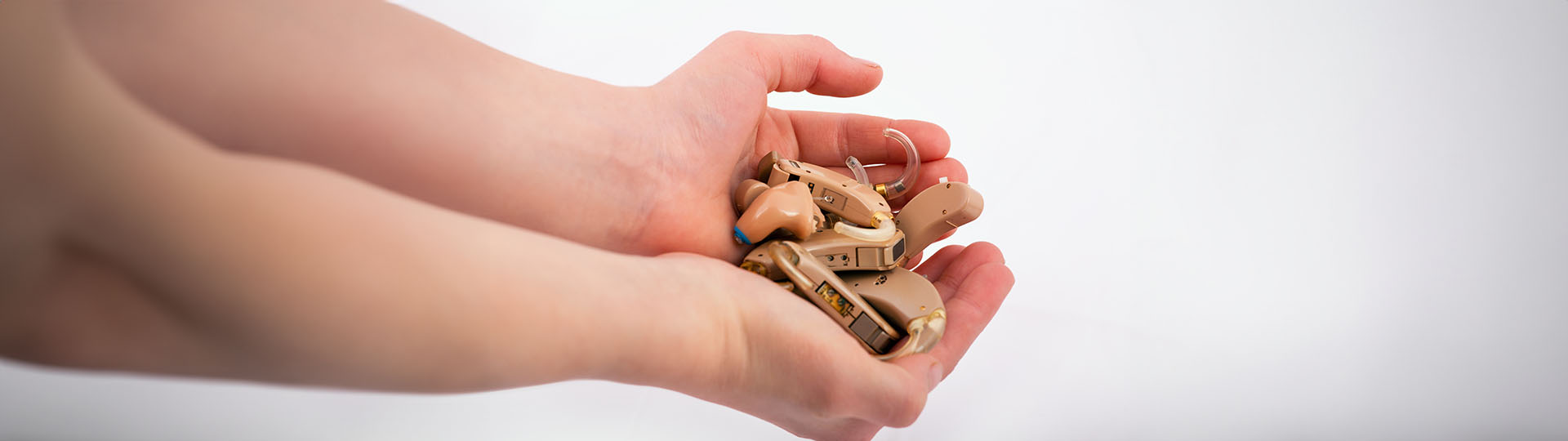 hands holding a collection of old hearing aids