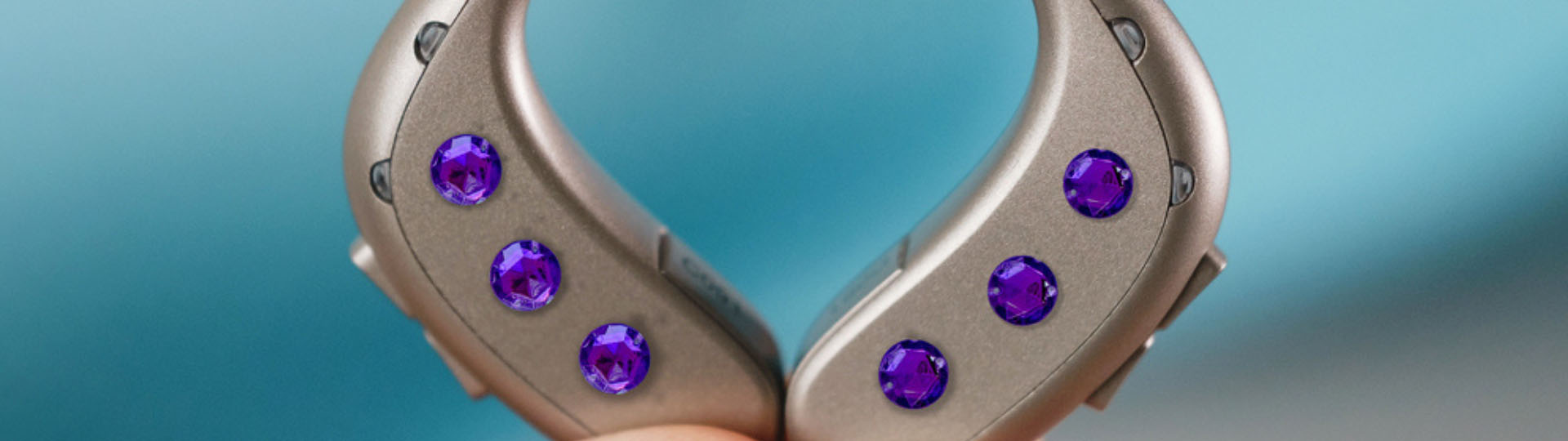 hearing aids decorated with vibrant purple gemstones on a gradient blue background