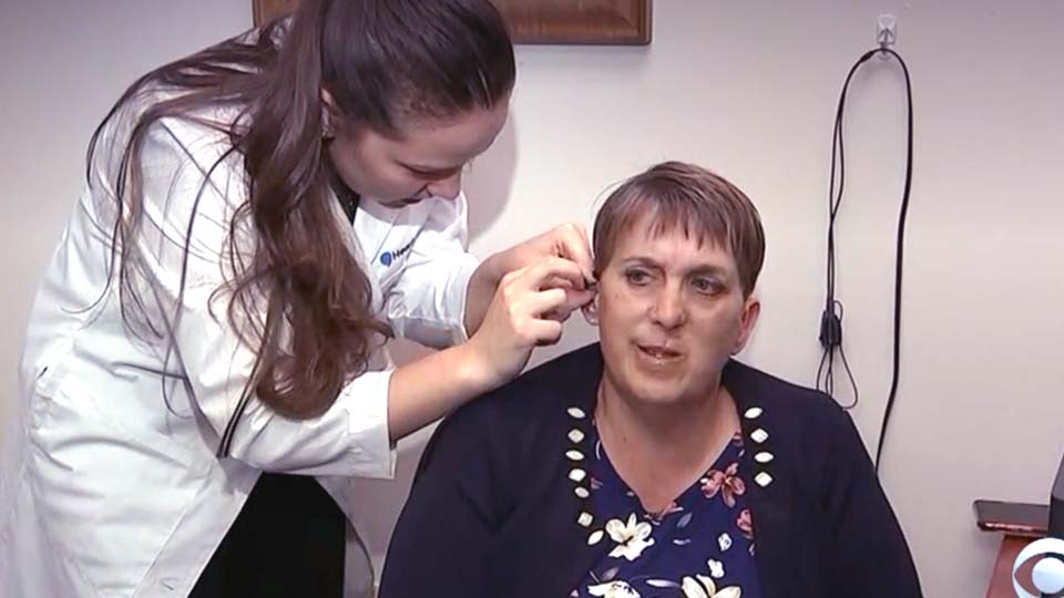hearing care specialist assisting a woman with hearing aid fitting