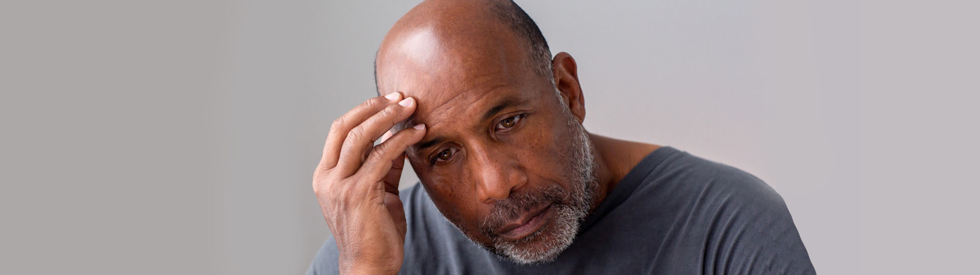 Man experiencing discomfort with a hand on his head – exploring tinnitus relief through hearing aids.