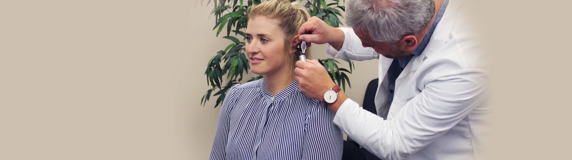 hearing care professional using an otoscope to check a woman's ear health