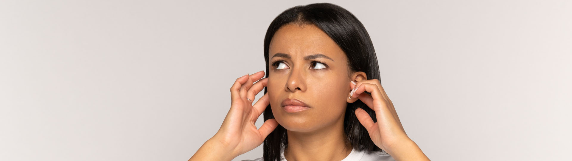 woman displaying discomfort from tinnitus while holding her ears