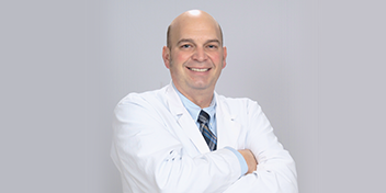 Hearing care professional in a white coat with arms crossed.