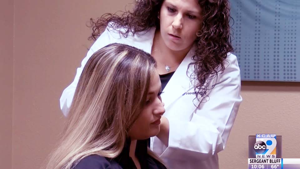 Hearing care specialist adjusting a hearing aid for a woman at a clinic.
