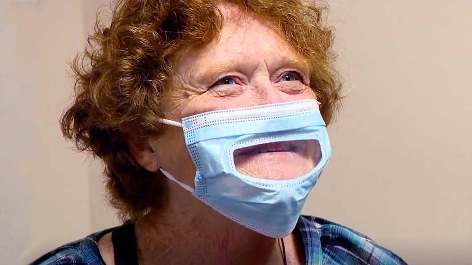 free hearing aids offered to enhance hearing for a woman wearing a mask with a transparent section