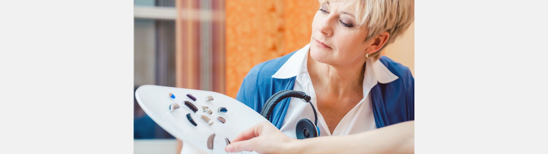 a woman looks at a display of different style hearing aids