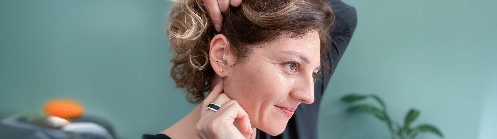 woman placing hearing aid in her ear