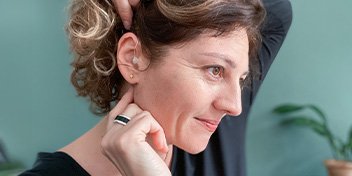 woman placing hearing aid in her ear